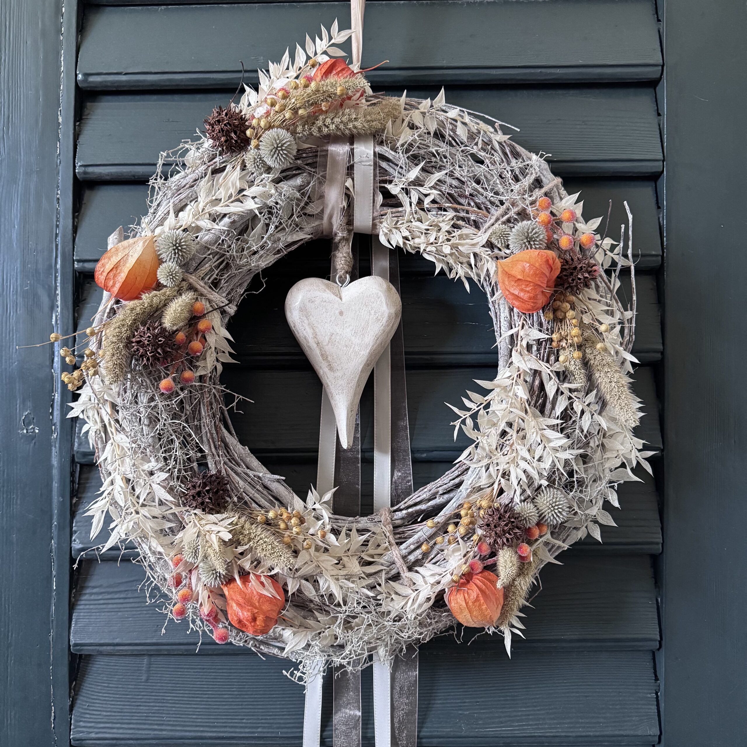 Handgemachter Herbst-Kranz aus weiss gekalkten Zweigen mit Naturmaterialien, Lampionblüten, Gräsern und Holzherz, dekoriert im Shabby-Chic-Stil.